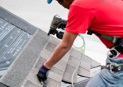 Photo of our Calgary roofers nailing new asphalt shingles to a roof