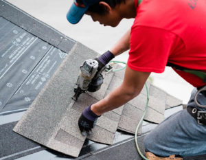 Photo of our roofer nailing asphalt shingles to a Calgary roof