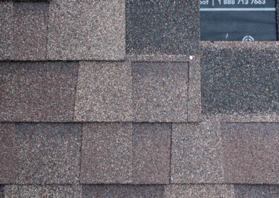 Photo of new asphalt shingles nailed overtop a woven synthetic roof underlay