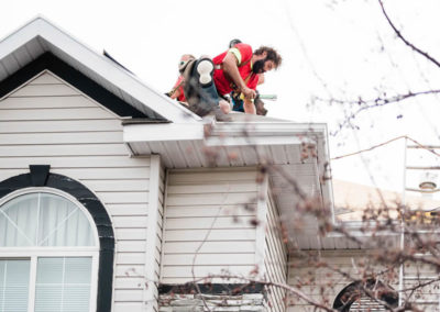 Photo of our Calgary roofer measuring the slope and angle of a roof's corner for repairs