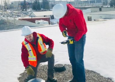 Photo of two of our roofers inspection a flat roof vent