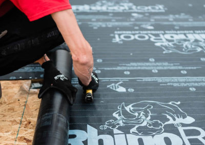 Close up photo of our roofer installing RhinoRoot synthetic roofing underlay to a Calgary roof