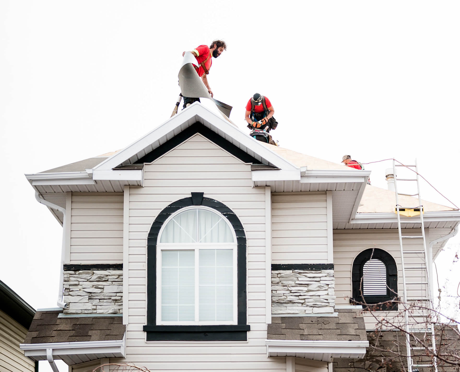 Photo of our roofers working on an asphalt shingle roof replacement on a suburban Calgary home.