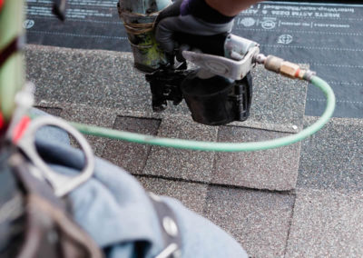 Up close photo of our roofer nailing asphalt shingles to a Calgary roof