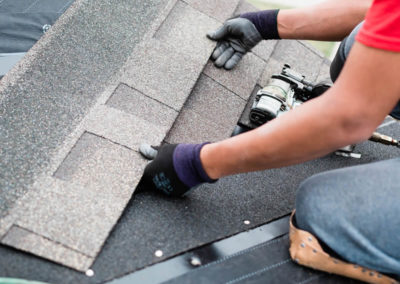 Photo of our Calgary roofer lining up new asphalt shingles before nailing them in place