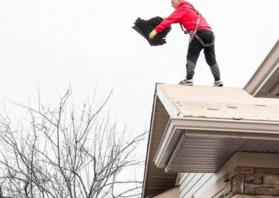 Photo of our roofers responsibly disposing of old shingle which is an important step for preparing your roof for fall.