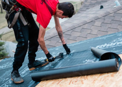 Photo of our roofer installing roofing underlay to a Calgary home