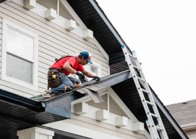 Photo of our roofer installing asphalt shingles to an entryway roof