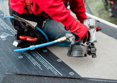 Close up photo of our roofer nailing new synthetic roof underlay to a Calgary roofing project