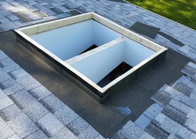 Photo of asphalt shingles being installed around a skylight