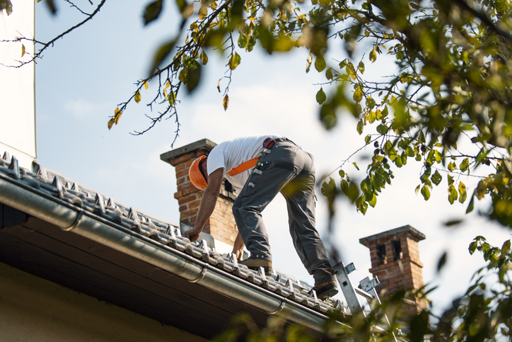 Roofer measuring chimney on roof top A house covered in snow and icicles