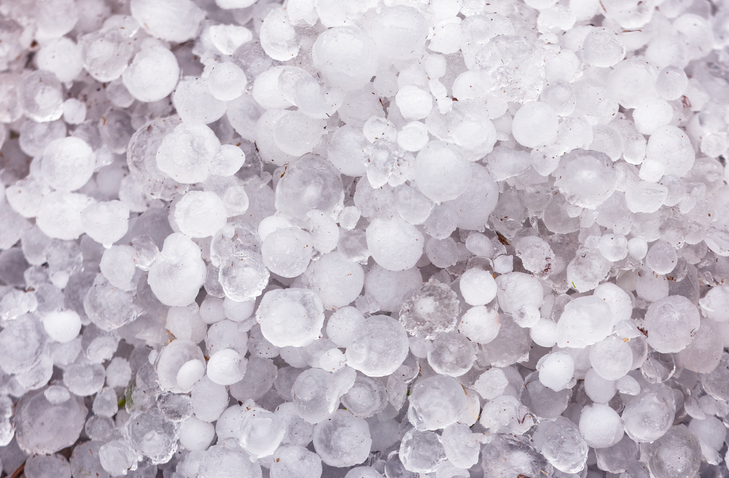 A pile of large hail on the ground A house covered in snow and icicles